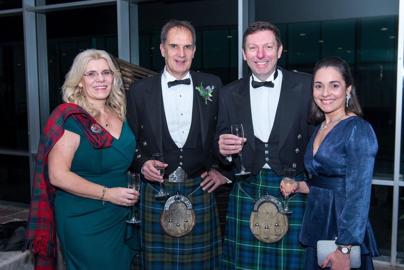 Guests raising a toast in formal dress and kilts