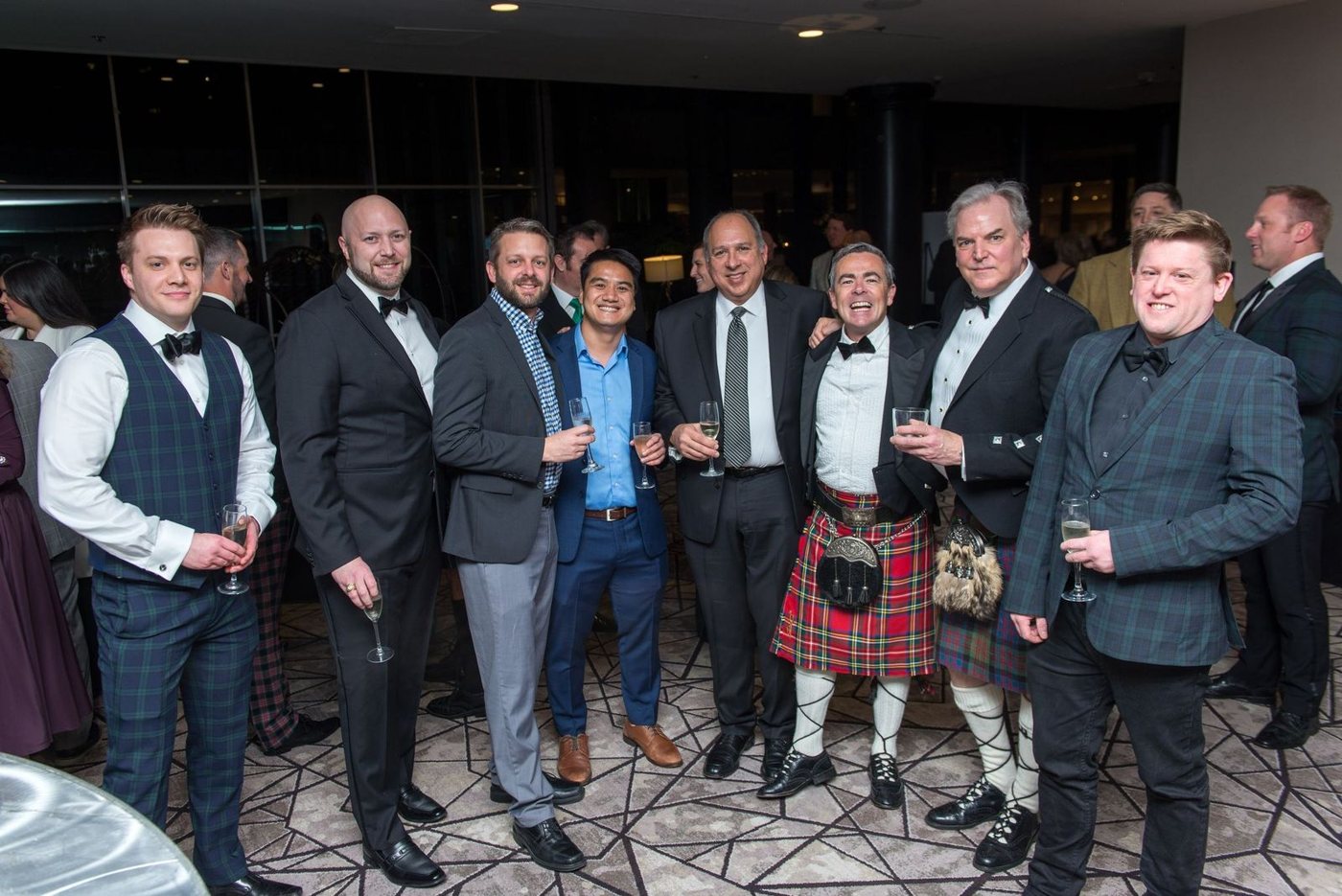 Friends in kilts and black-tie sharing a laugh
