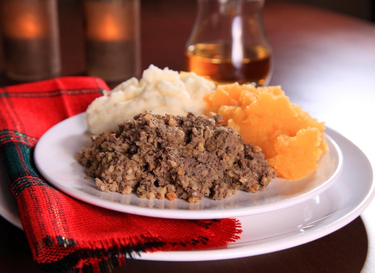 Traditional haggis with neeps and tatties, served beside a wee dram of whisky